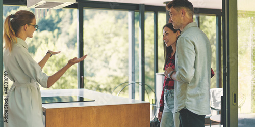 Side view of real estate agent showing couple modern house in the mountains 