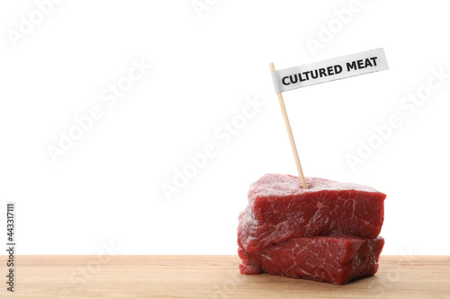 Pieces of raw cultured meat with toothpick label on wooden table against white background