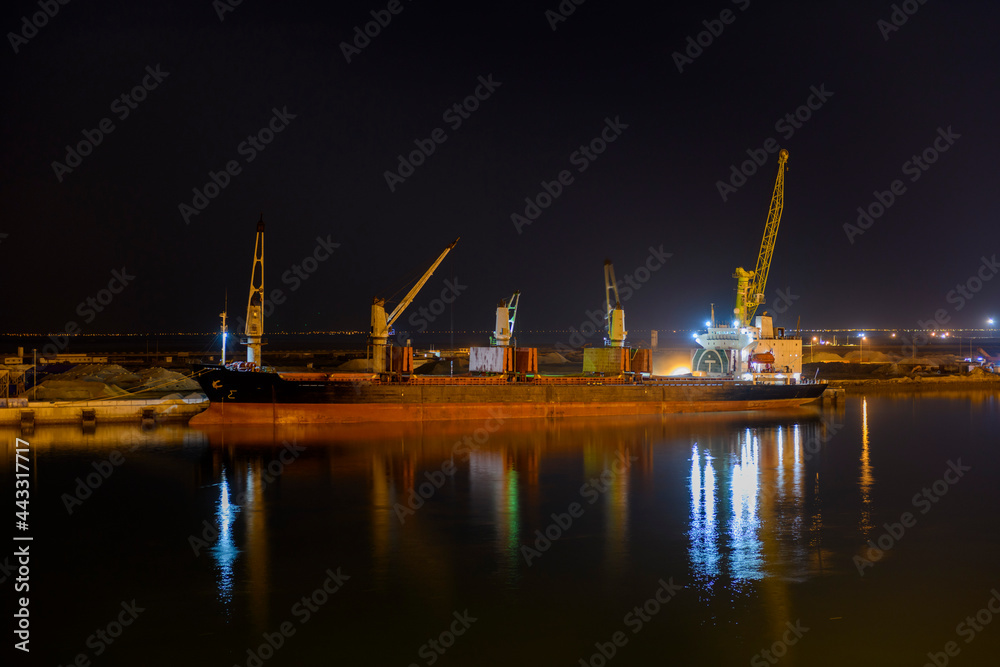 Bulk carrier vessel moored alongside berth in port. Night view. Bulker. Dry cargo ship. Bulk carrier vessel moored alongside berth in port. Night view. Bulker. Dry cargo ship.