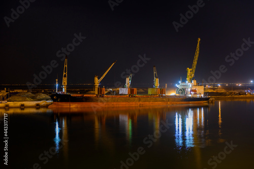 Bulk carrier vessel moored alongside berth in port. Night view. Bulker. Dry cargo ship.