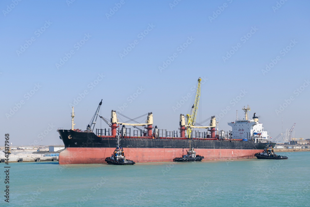Vessel approaching to berth with tugs assistance. Mooring operations. Bulker. Dry cargo ship..