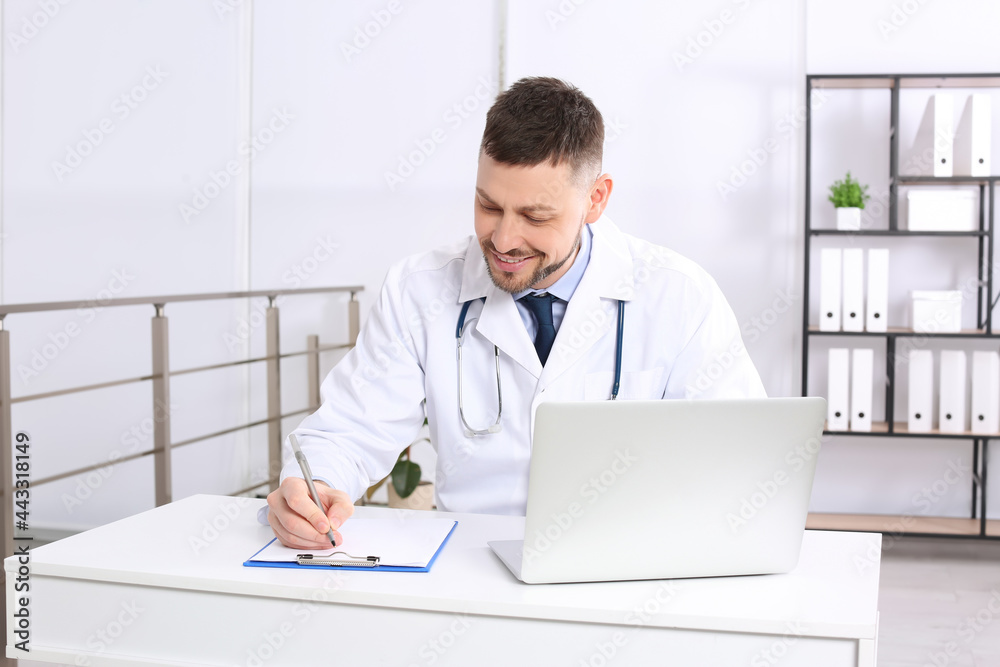 Fototapeta premium Pediatrician working on laptop at desk in office