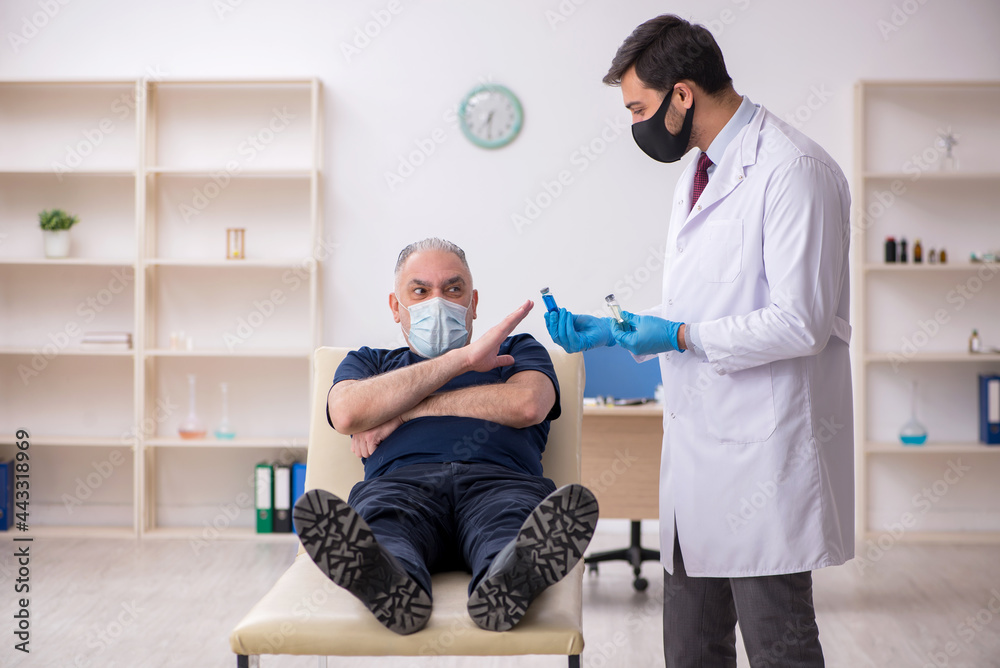 Fototapeta premium Old male patient visiting young male doctor in vaccination conce