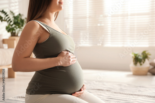 Young pregnant woman practicing yoga at home, closeup. Space for text photo