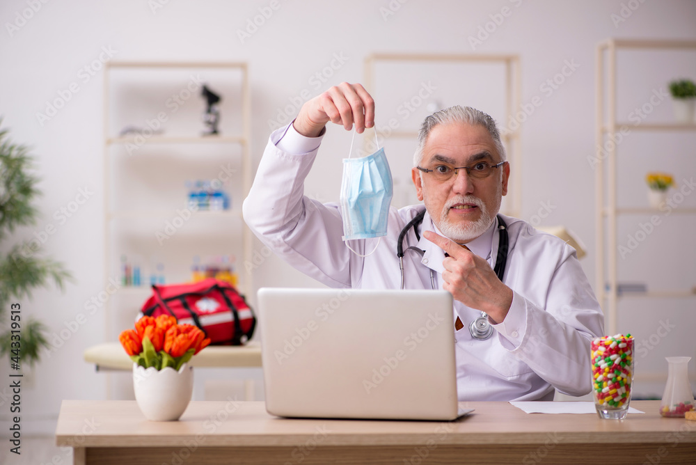 Old male doctor working in the clinic during pandemic Old male doctor working in the clinic during pandemic