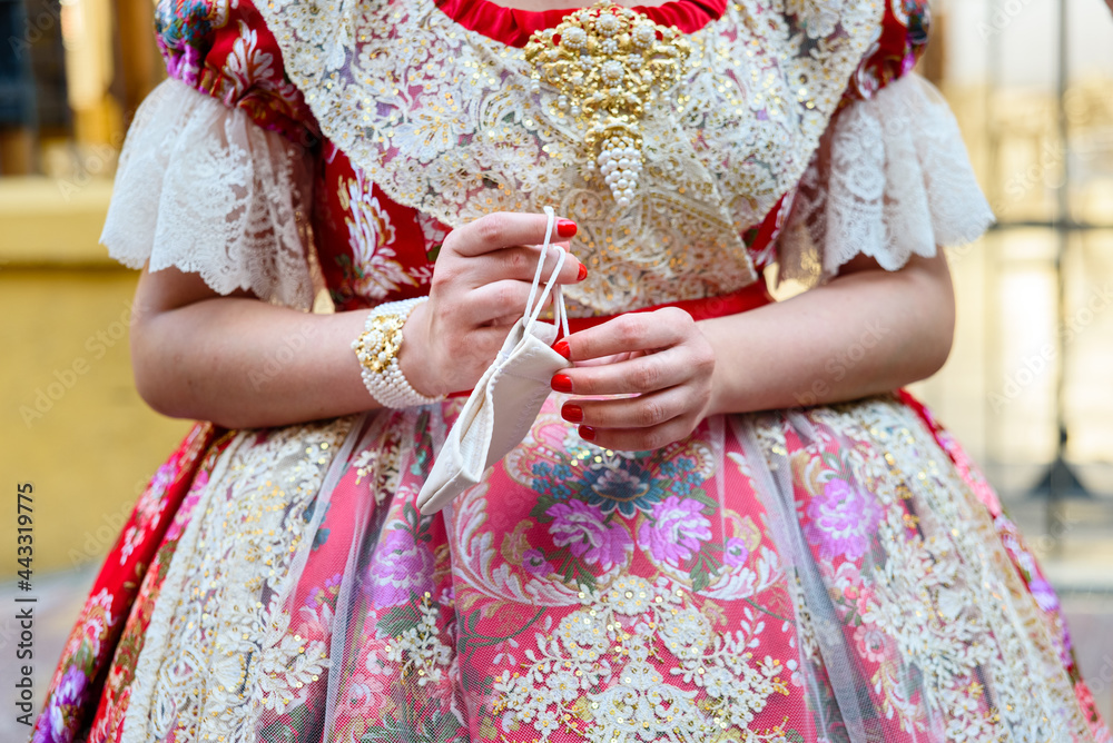Detail of a Valencian Fallas woman taking off her mask during the Fallas festivities of 2021.