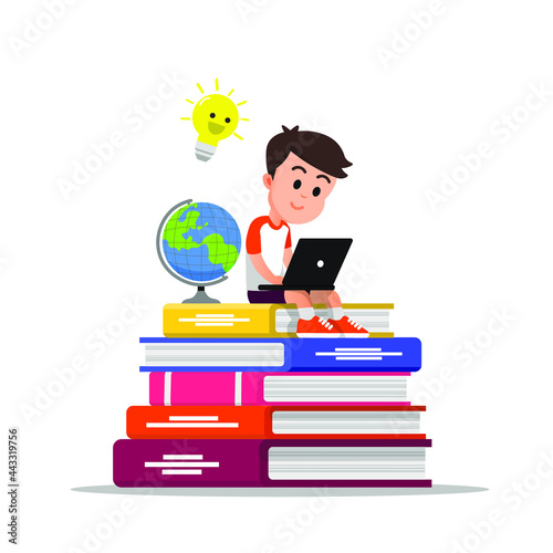 boy using a laptop while sitting on a pile of big books