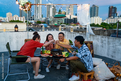 Group of Asian millennial people friends toasting alcoholic drink shot glasses while having outdoor dinner party with eat barbecue grill at rooftop for meeting reunion and holiday celebration together
