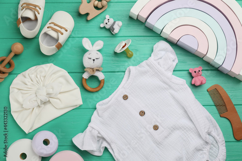 Flat lay composition with baby clothes and accessories on turquoise wooden table
