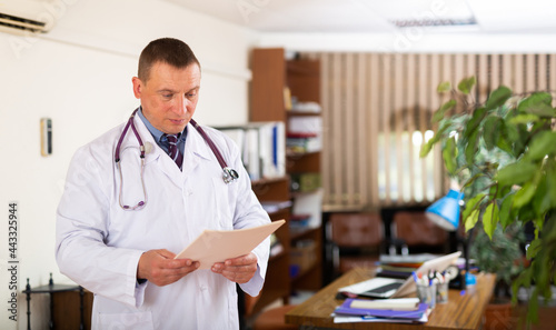 Portrait of focused man doctor working with medical documents in clinic office
