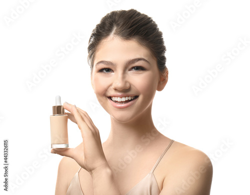 Beautiful girl with bottle of foundation on white background