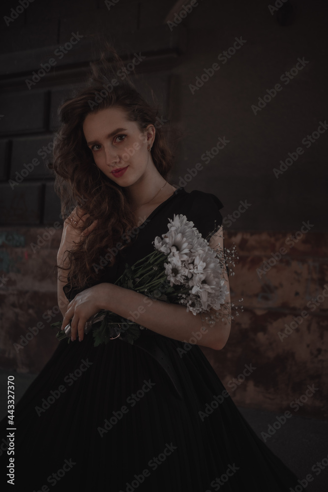 Curly girl in a black dress against the backdrop of the city