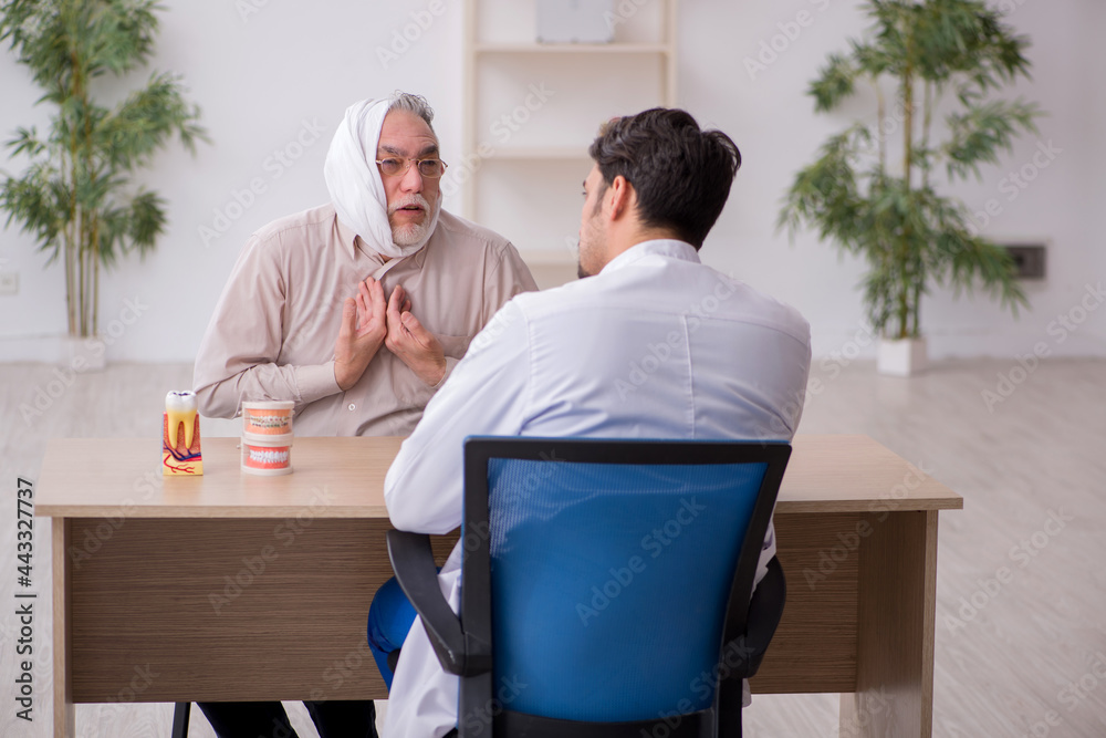 Obraz premium Old male patient visiting young male doctor dentist