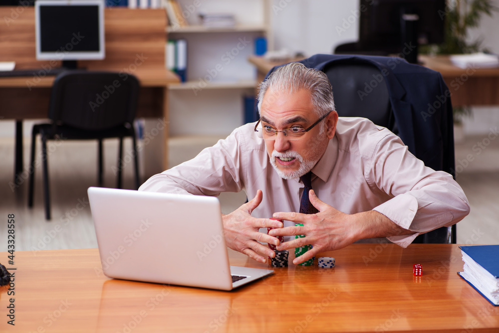 Old male employee in gambling concept at workplace