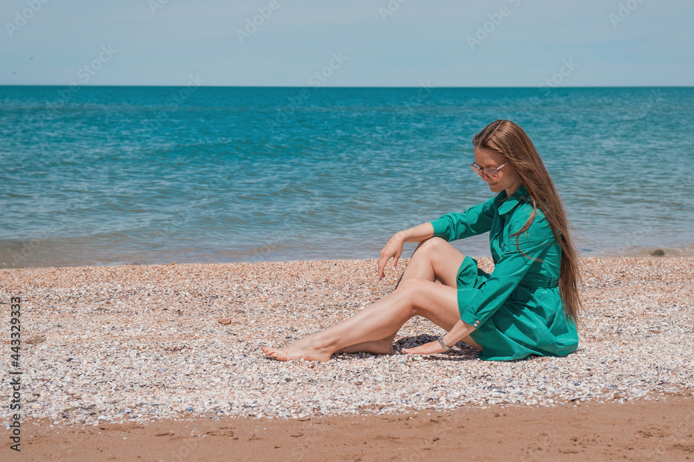 a girl with long hair in a green dress on the beach. beach holidays a girl with long hair in a green dress on the beach. beach holidays