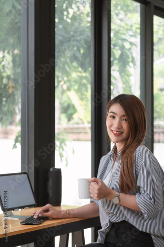 Image of a charming Asian woman working at a coffee shop cafe. Female freelance using digital tablet