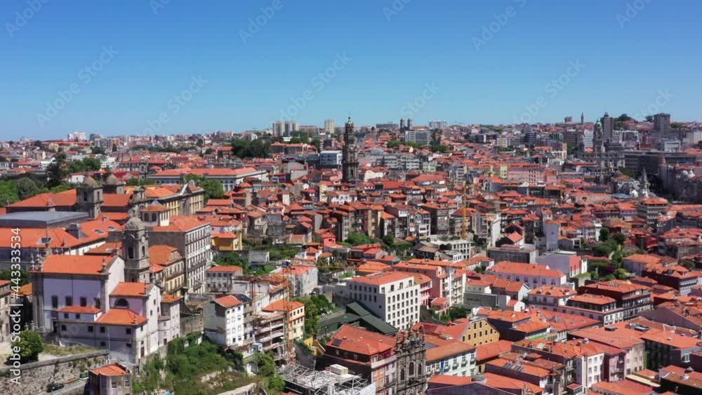 Aerial flight towards Clerigos Tower surrounded by red roof of old buildings in Oporto. Beautiful weather outdoors with blue sky and sun. Cinematic drone shot. Aerial flight towards Clerigos Tower surrounded by red roof of old buildings in Oporto. Beautiful weather outdoors with blue sky and sun. Cinematic drone shot.