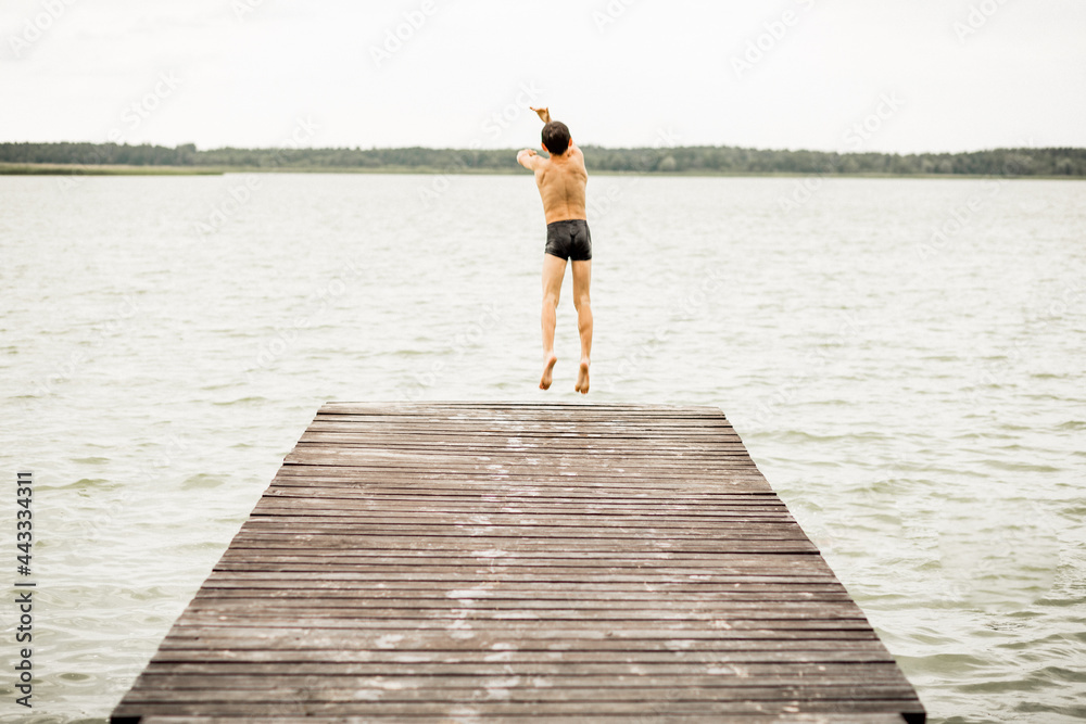 One boy jumping into water, rear view, summer time, vacations