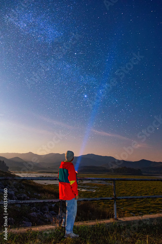 noise in the universe with grain Long exposure photography night light, Man wearing winter cloth standing next to the pointing the milky way with a flashlight