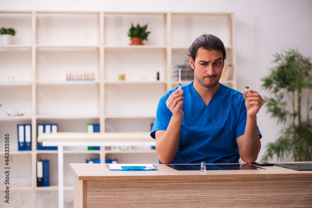 Young male doctor holding syringe in the clinic Young male doctor holding syringe in the clinic