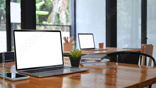 Mock up laptop and mobile phone on wooden table in meeting room. © Prathankarnpap