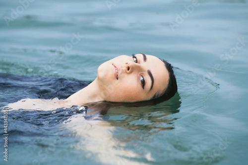 A dark-haired girl swims in the lake and takes a photo session