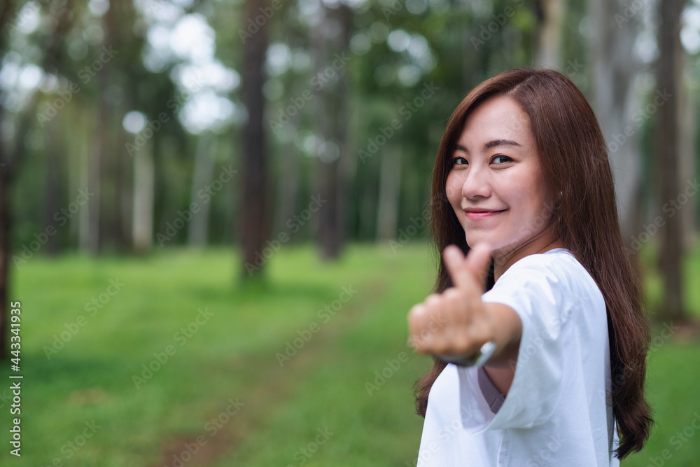 A beautiful asian woman making mini heart hand sign in the park A beautiful asian woman making mini heart hand sign in the park