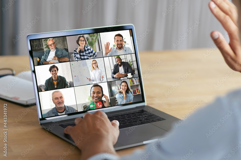 Online meeting, group brainstorming concept. Successful man waving his hand at the laptop computer screen, greeting employees during an video conference Online meeting, group brainstorming concept. Successful man waving his hand at the laptop computer screen, greeting employees during an video conference