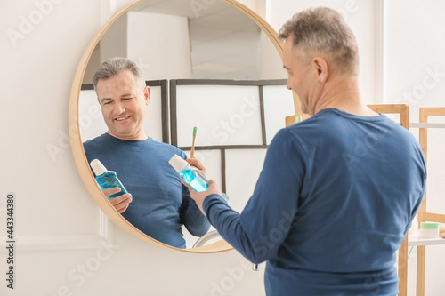 Mature man brushing teeth at home