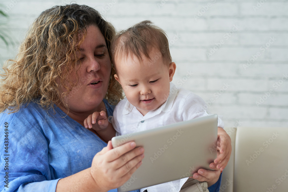 Mother and her little son watching animated cartoon on tablet computer when staying home due to coronavirus pandemic Mother and her little son watching animated cartoon on tablet computer when staying home due to coronavirus pandemic