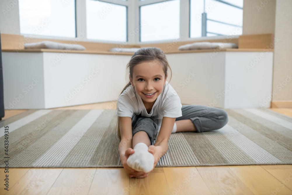 Cute girl sitting on the floor and stretching Cute girl sitting on the floor and stretching