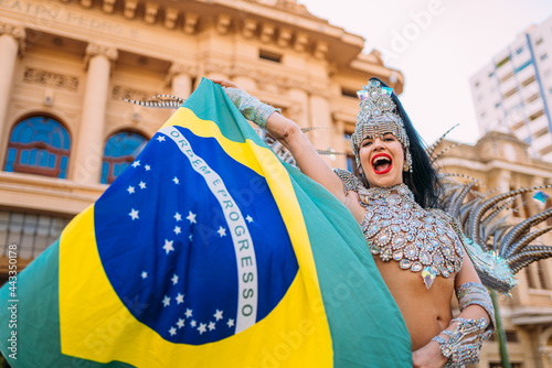 Beautiful Brazilian woman wearing colorful Carnival costume and Brazil flag during Carnaval street parade in city. photo