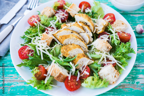 Caesar salad with chicken breast on a rustic background, tomatoes, parmesan, green salad and croutons, selective focus