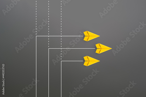New normal concept with Group of yellow paper planes in new direction on gray background