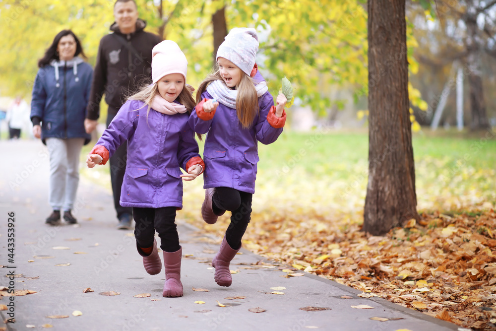 Obraz premium Young family on a walk in the autumn park on a sunny day. Happiness to be together.