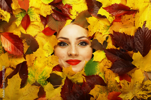 Artistic conceptual autumn girl portrait. Colorful leaves. Leaves of trees around an emotional face. Autumn is coming.