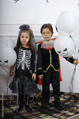 Happy family with children in costumes of witch and vampire in a house in holiday Halloween