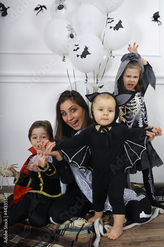 Happy family with children in costumes of witch and vampire in a house in holiday Halloween