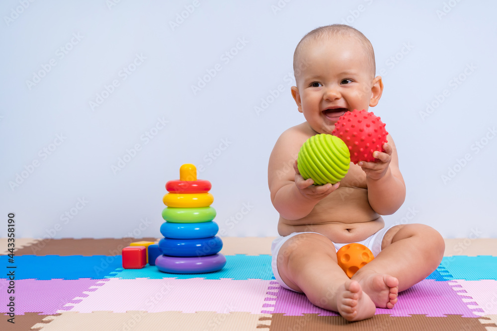 Happy newborn baby playing with rubber balls in playroom Happy newborn baby playing with rubber balls in playroom