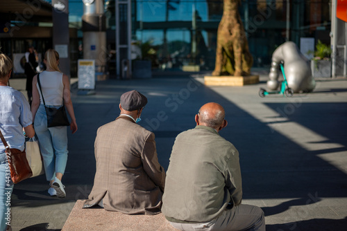 Two senior men sitting on the street outside Oslo Central station in the summer.