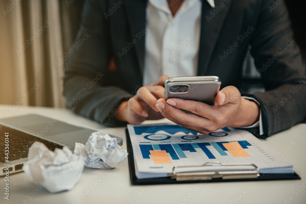 Fototapeta premium Business documents on office desk with smart phone and graph business diagram and man working at office.