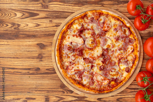 Top view of freshly baked pizza on wooden background