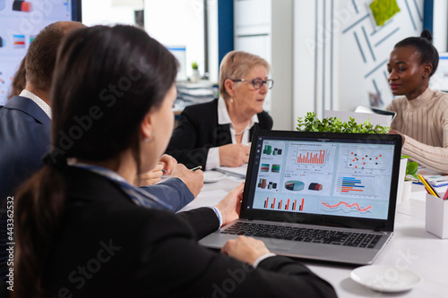 Young woman analysing charts on laptop in start up business meeting room. Multiethnic coworkers breefing team diverse people leadership. African employee listening senior manager.