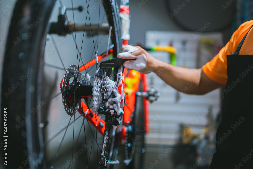Bicycle mechanic. He is cleaning, washing bikes. Road bikes. - obrazy, fototapety, plakaty 