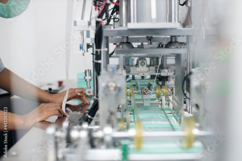 Asian worker hands inspecting quality of mask and medical face mask production line, Industry and factory concept.