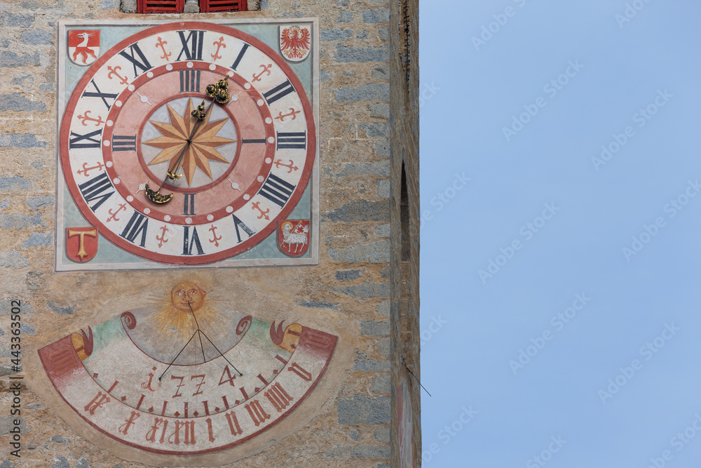 Obraz premium The recently restored clock and sundial painted outside the bell tower of the church of the town.
