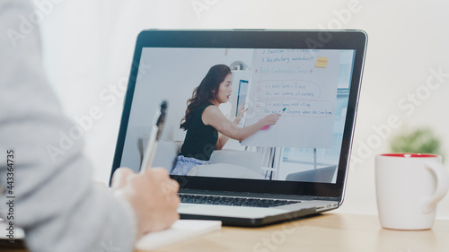 Young Asia teen girl university student using laptop computer distance learn lesson with female teacher remote teaching on internet at home. Social distancing  quarantine for corona virus prevention.