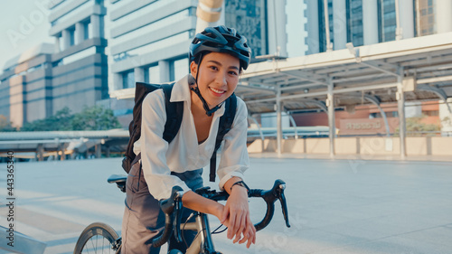 Bild auf Leinwand Asian businesswoman go to work at office stand and smiling wear backpack look at camera with bicycle on street around building on a city