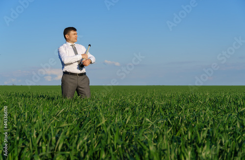 businessman poses with a spyglass  he looks into the distance and looks for something  green grass and blue sky as background