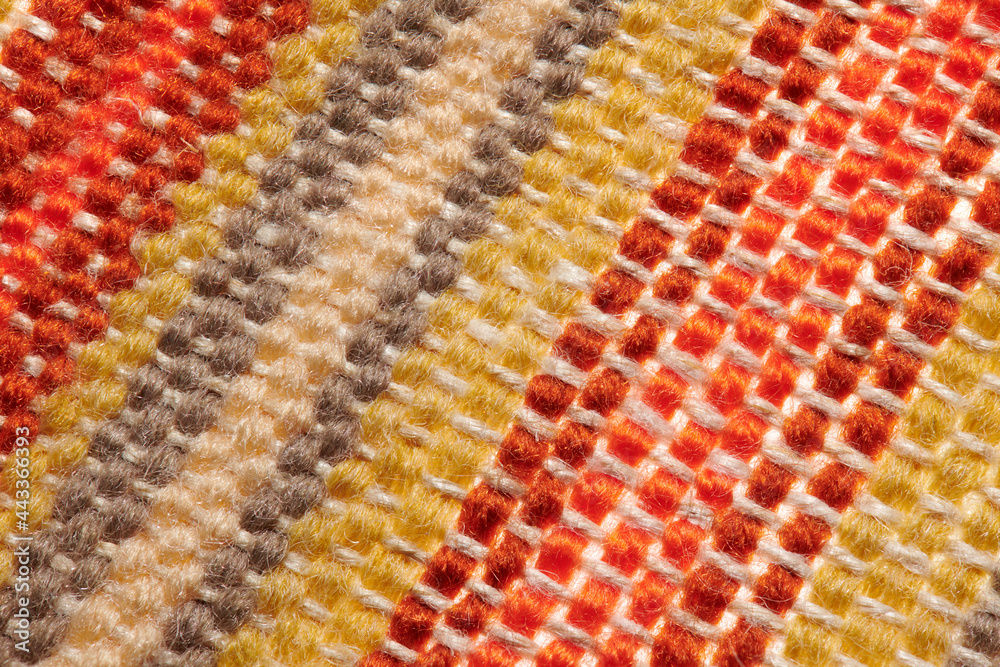 a small handmade rug or mat, woven from red and yellow wool threads, one object close-up